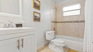 Un baño con tocador blanco, inodoro, bañera y ducha.