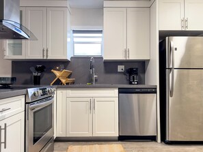 A modern kitchen with stainless steel appliances, white cabinetry, and a window above the sink.