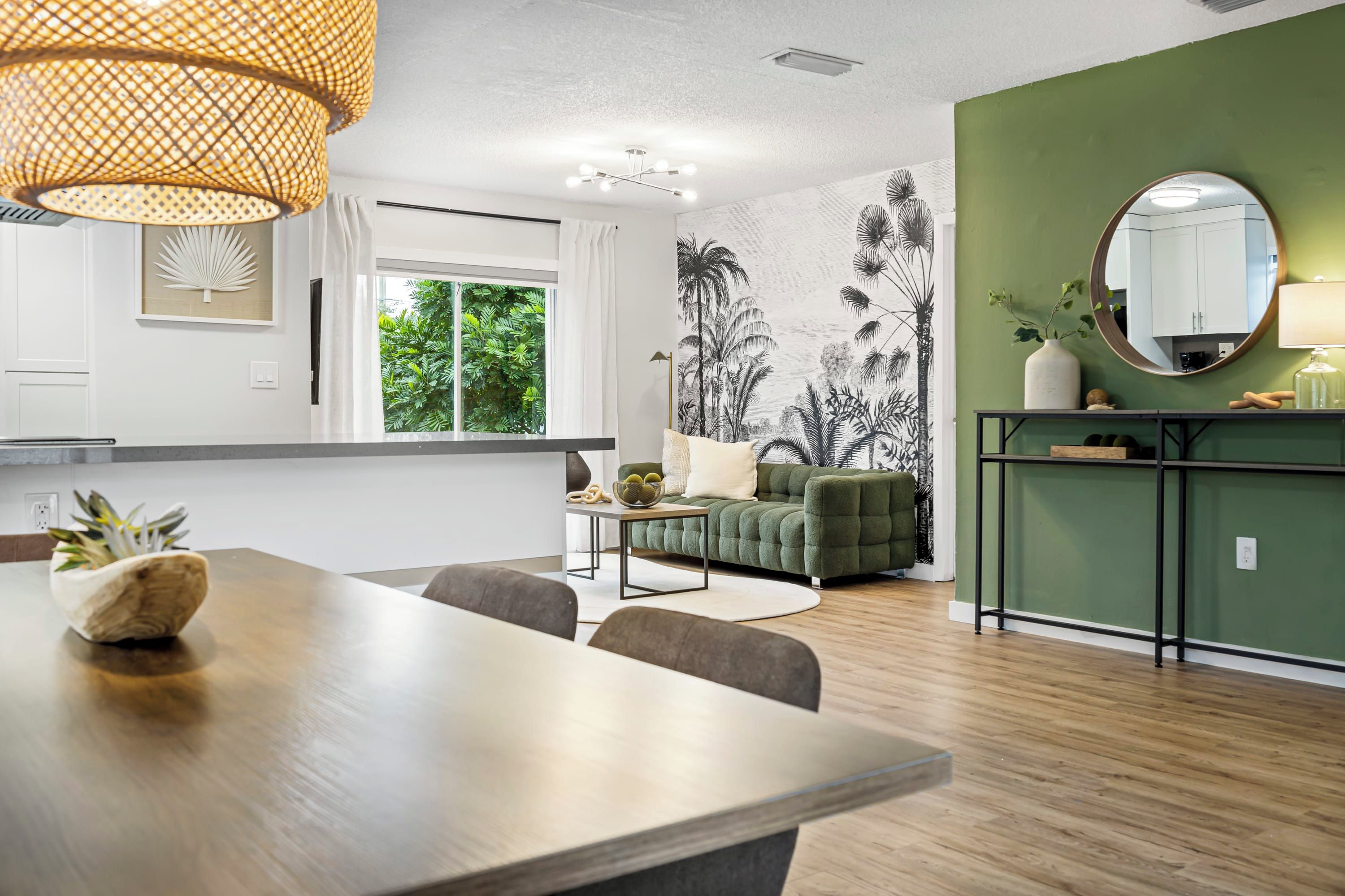 Una cucina moderna con zona pranzo, una parete verde decorativa e un'ampia finestra.