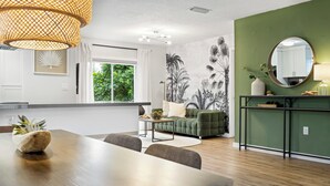 Una cocina moderna con comedor, pared de acento verde y un amplio ventanal.