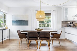 A modern kitchen with a dining table, chairs, and a hanging light fixture.