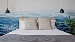 A bed with a headboard, two pillows, a grey textured bedspread, and a wall mural of water. - Bayshore Bliss, Cozy With Water Views of Miami Bay (North Bay Village)