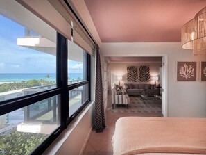 A hotel room with a large window, a bed, a sofa, and a view of the ocean. - Coastal Dreams, Serene, Beachfront With Pool (Miami Beach)