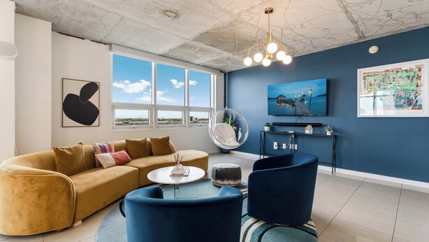 A living room with a sofa, chairs, a coffee table, a hanging chair, a TV, and artwork on the wall. - Miami Vice, Chic, Pool and Steps to Midtown Shops (Miami)
