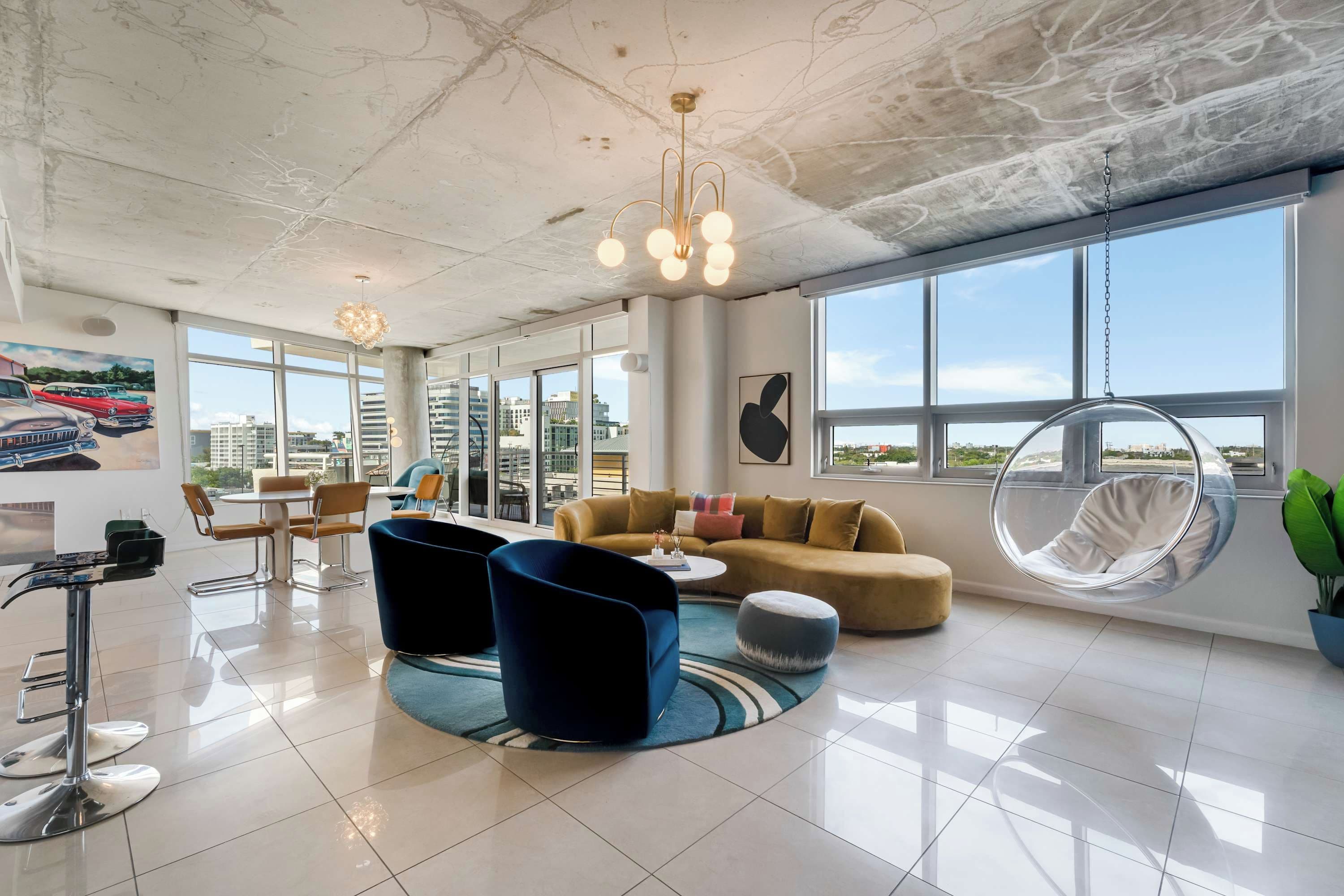A modern hotel lobby with a large window, a hanging chair, and a round coffee table.
