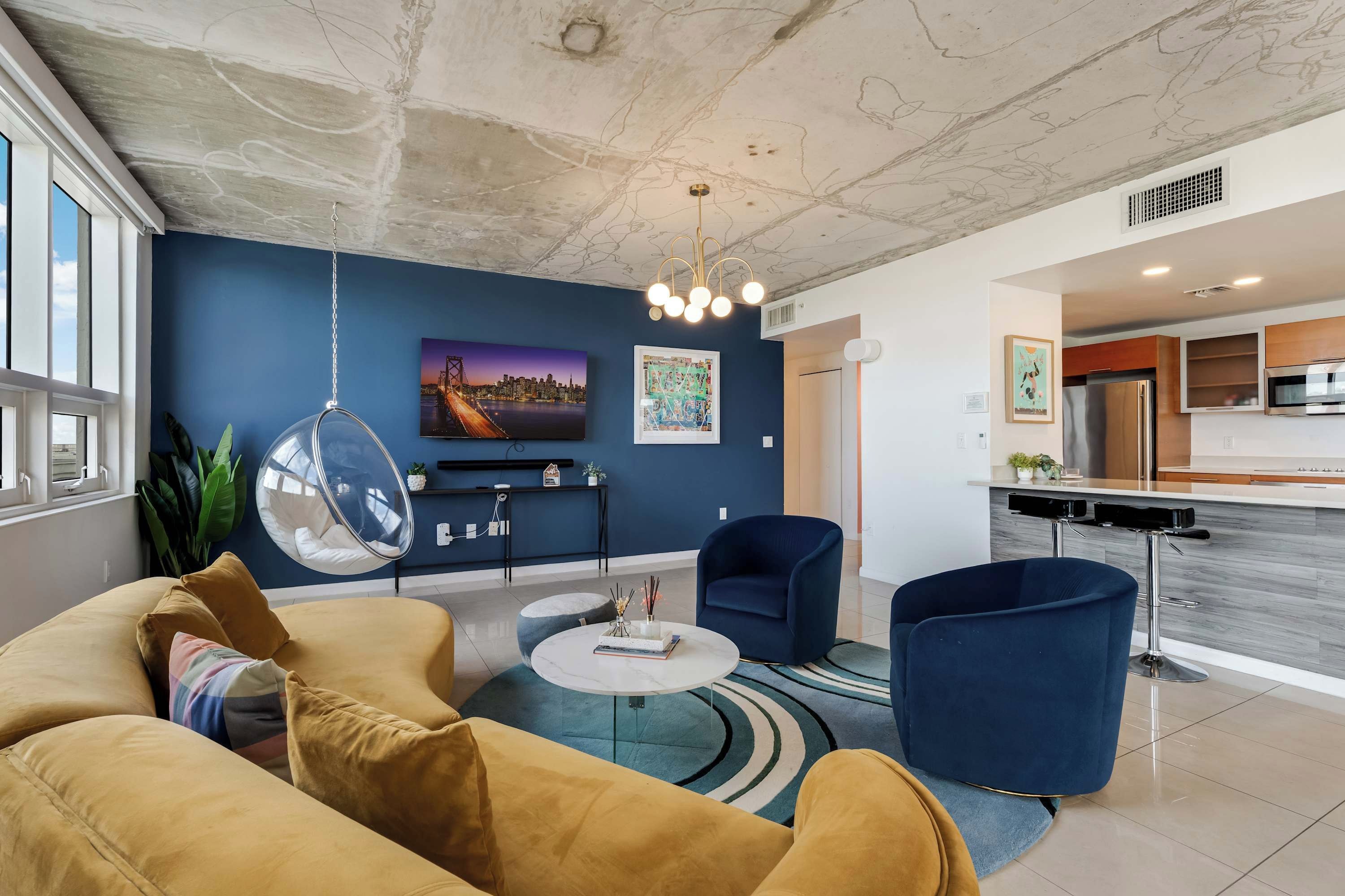 Uma sala de estar moderna com sofá, poltrona, mesa de centro e cadeira suspensa.