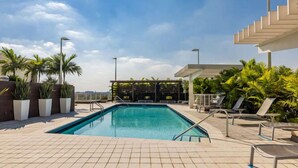 A rooftop pool with tiled flooring, lounge chairs, and palm trees. - Miami Vice, Chic, Pool and Steps to Midtown Shops (Miami)