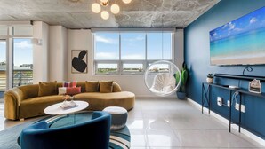 A modern living room with a sofa, coffee table, and a hanging chair. - Miami Vice, Chic, Pool and Steps to Midtown Shops (Miami)