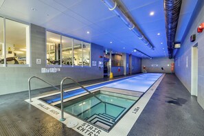 An indoor swimming pool with clear lane markings, a shallow water area, and a no diving sign.