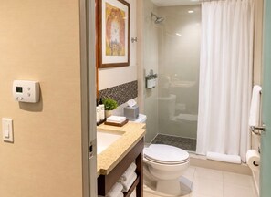 A bathroom with a toilet, sink, shower, and a glass-enclosed shower stall.