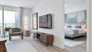 A modern hotel room with a bed, a seating area with a chair, a small table, and a wall-mounted TV. - Relaxing Cloud 9, Central Brickell Location (Miami)