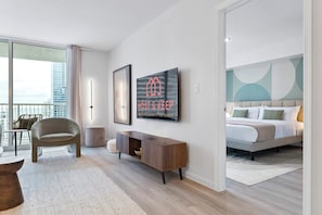 A modern hotel room with a bed, a seating area with a chair, a small table, and a wall-mounted TV. - Relaxing Cloud 9, Central Brickell Location (Miami)