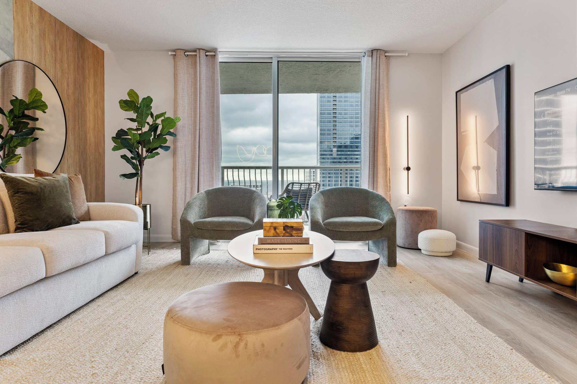 A modern living room with a sofa, two armchairs, a coffee table, and a bookshelf.