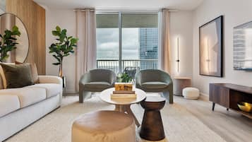 A modern living room with a sofa, two armchairs, a coffee table, and a bookshelf.