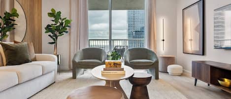 A modern living room with a sofa, two armchairs, a coffee table, and a bookshelf.