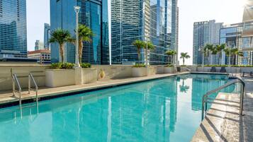 A swimming pool with clear blue water, surrounded by modern high-rise buildings.