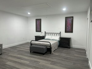 Ein Schlafzimmer mit einem Bett, Nachttischen, einer Bank und zwei an der Wand befestigten Bildern.