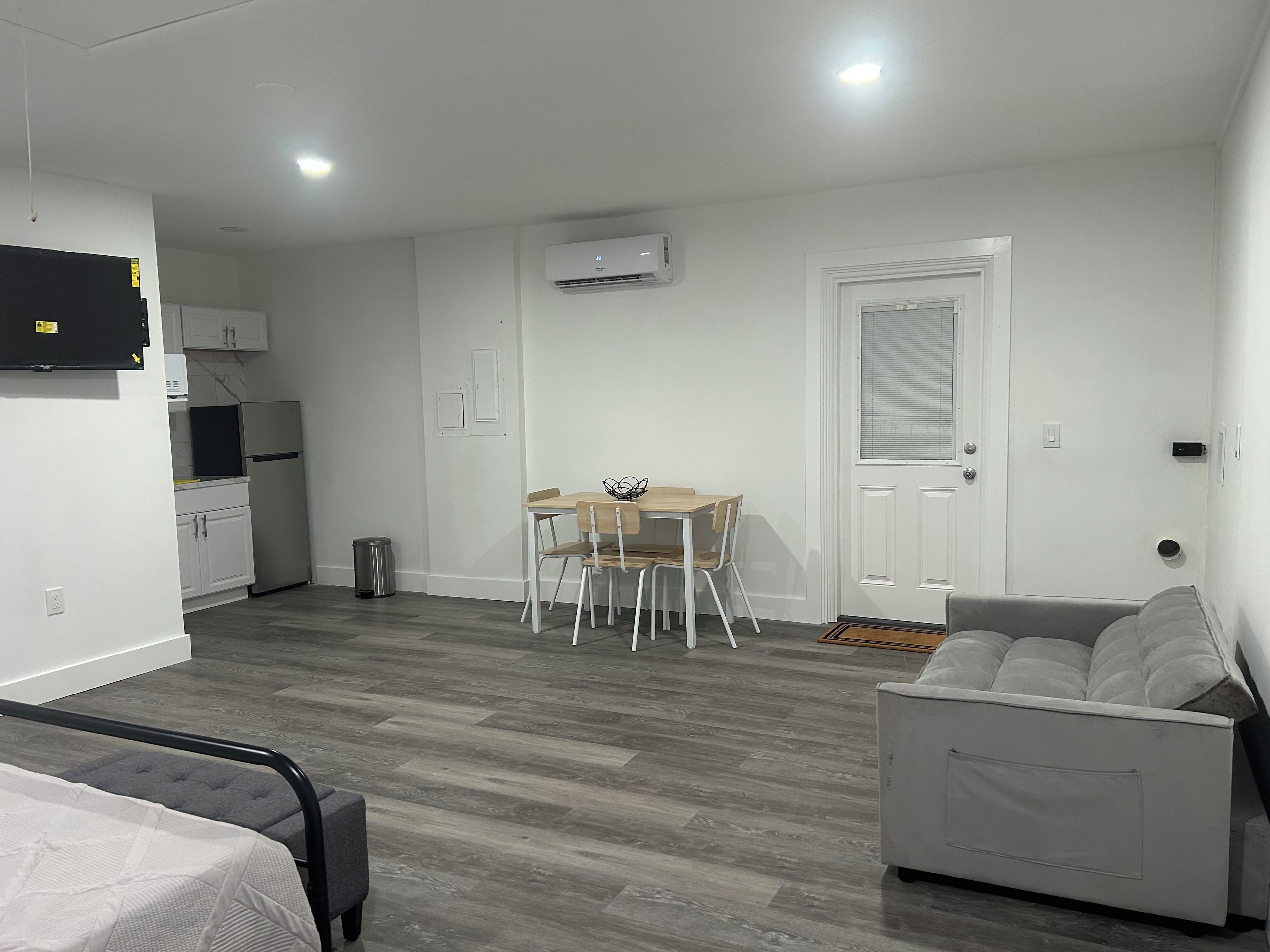 A compact living space with a kitchenette, a dining area, and a seating area with a sofa and a chair.