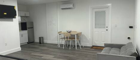 A compact living space with a kitchenette, a dining area, and a seating area with a sofa and a chair.