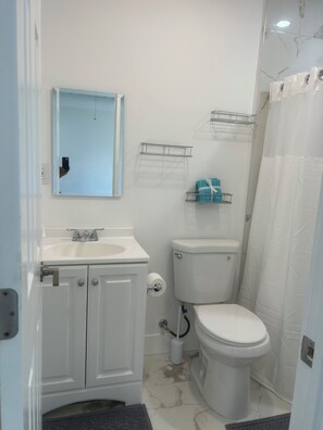 Ein Badezimmer mit weißem Waschbecken, Spiegel, Toilette und Duschvorhang.