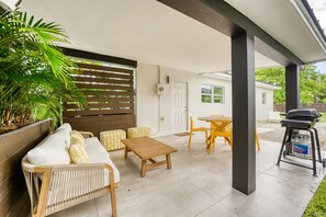 An outdoor patio area with a sofa, two ottomans, a table, and chairs. - Casa Ana, Homey Design, Hot Tub in North Miami (Miami Shores)