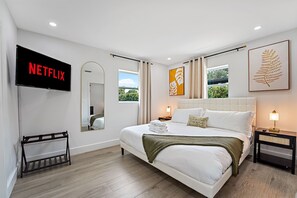 A modern hotel room with a large bed, a flat-screen TV, a mirror, and artwork on the walls. - Casa Ana, Homey Design, Hot Tub in North Miami (Miami Shores)
