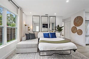 A modern bedroom with a bed, seating area, and large windows. - Casa Ana, Homey Design, Hot Tub in North Miami (Miami Shores)