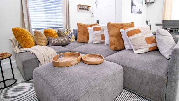 A modern living room with a grey sectional sofa, wooden trays, and a 'FAMILY' pillow. - Good Vibes Oasis, 2 Story Townhome in Cutler Bay (Cutler Bay)