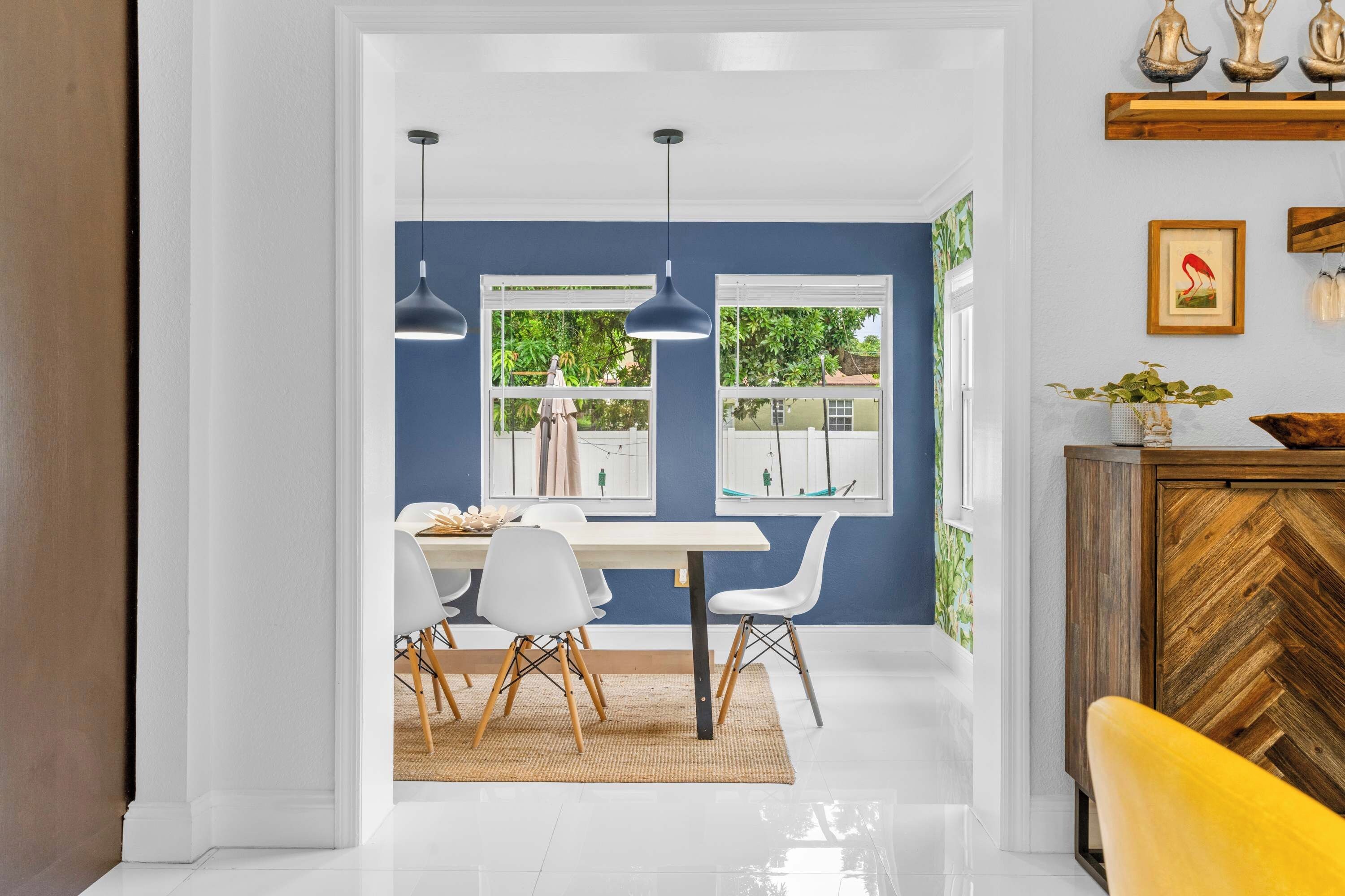 A dining area with a white table, white chairs, and a wooden herringbone cabinet.