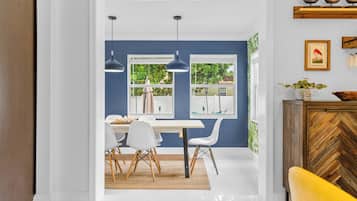A dining area with a white table, white chairs, and a wooden herringbone cabinet.