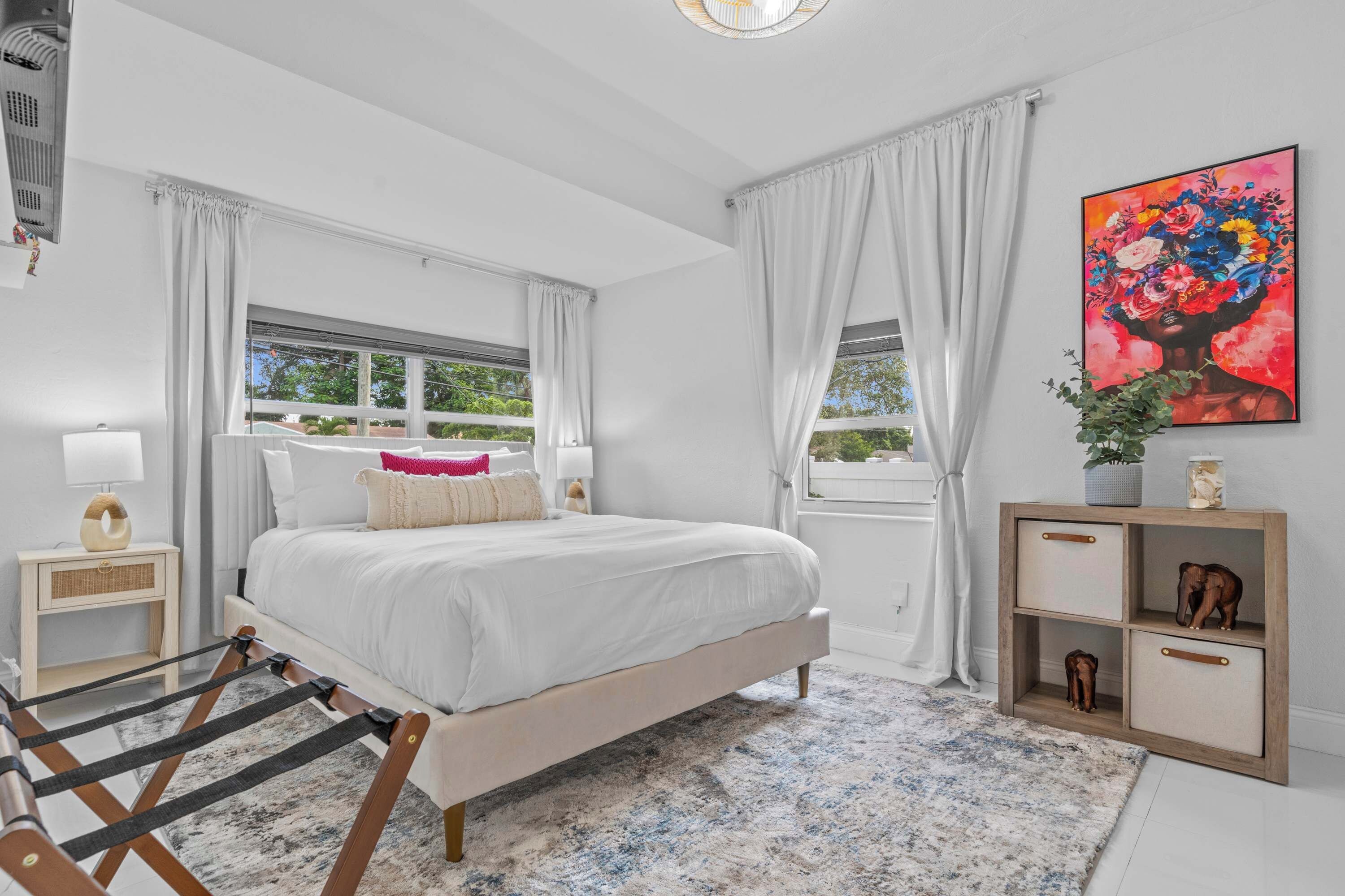 A bedroom with a bed, a nightstand, a wooden cabinet, and a window with curtains.