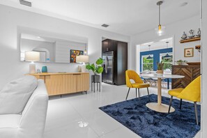 A modern kitchen with a built-in refrigerator, a wooden dining table with yellow chairs, and a blue rug.