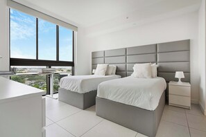 Quarto moderno com duas camas, uma escrivaninha e uma mesinha de cabeceira.