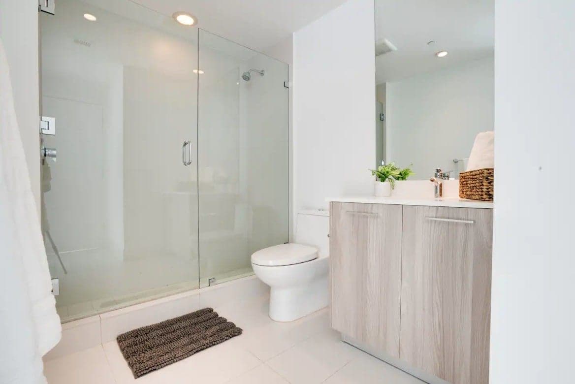 Une salle de bain moderne avec une douche à parois de verre, des toilettes et un meuble-lavabo en bois.