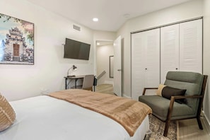 A bedroom with a bed, a desk, a chair, a TV, and a wardrobe.