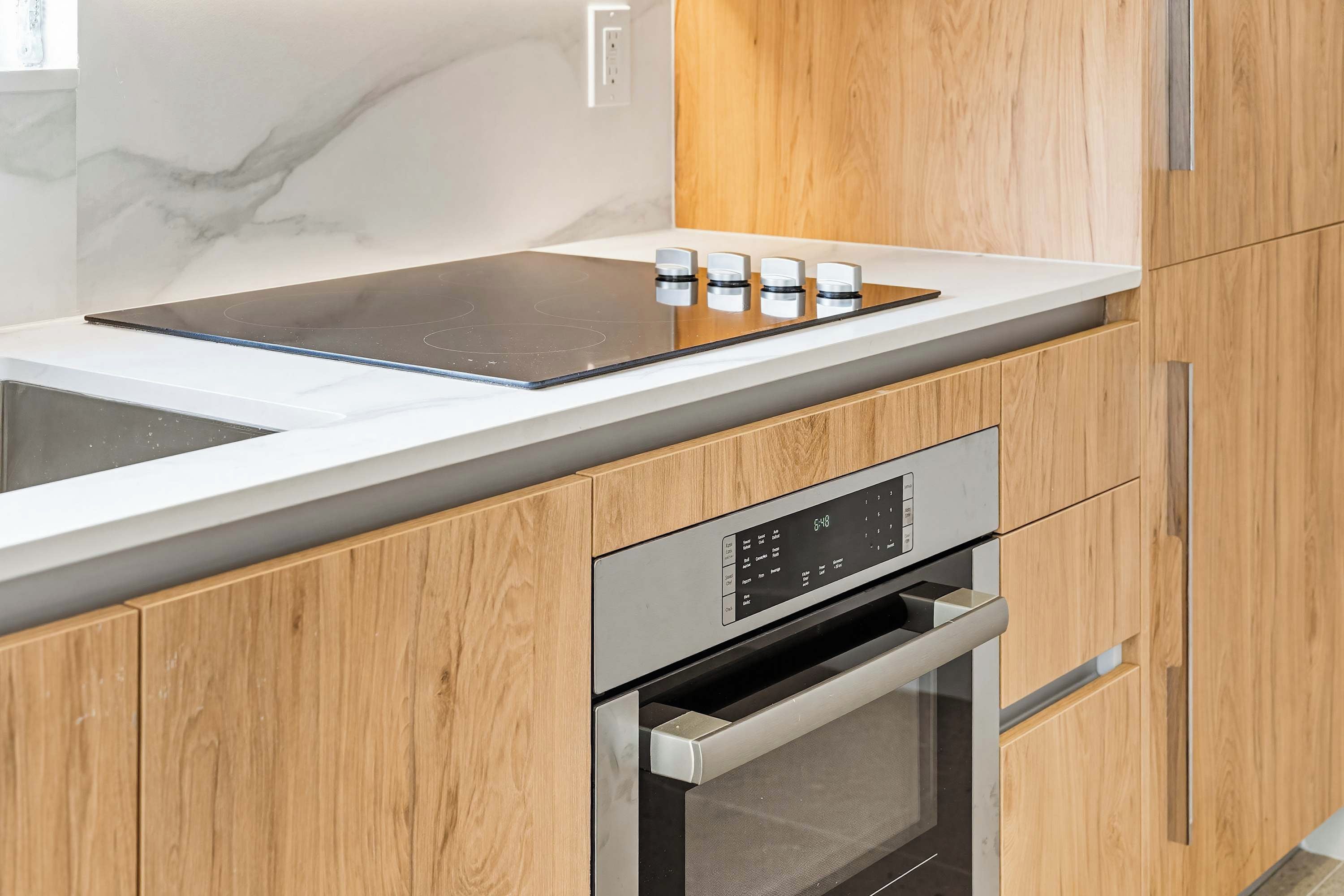 Une cuisine moderne équipée d’un four encastré, d’une plaque de cuisson et d’un four à micro-ondes.