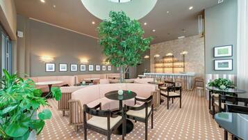 A modern lounge area with a central tree, seating arrangements, and a patterned floor.