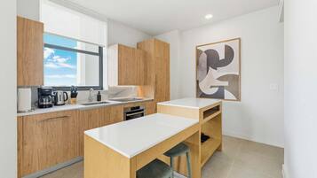 A modern kitchen with wooden cabinets, a white countertop, and a large window.