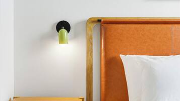 A bedroom with a wooden headboard, a bedside table, and a wall-mounted light fixture.