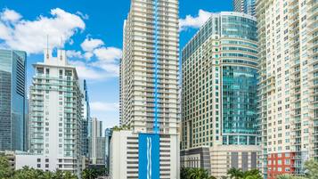Un paysage urbain avec des immeubles modernes de grande hauteur, dont un bâtiment blanc remarquable orné d’une bande verticale bleue et un bâtiment aux façades courbes en verre.