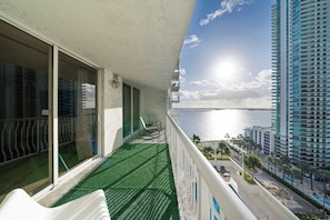 Uma varanda com vista para o mar e um edifício alto.