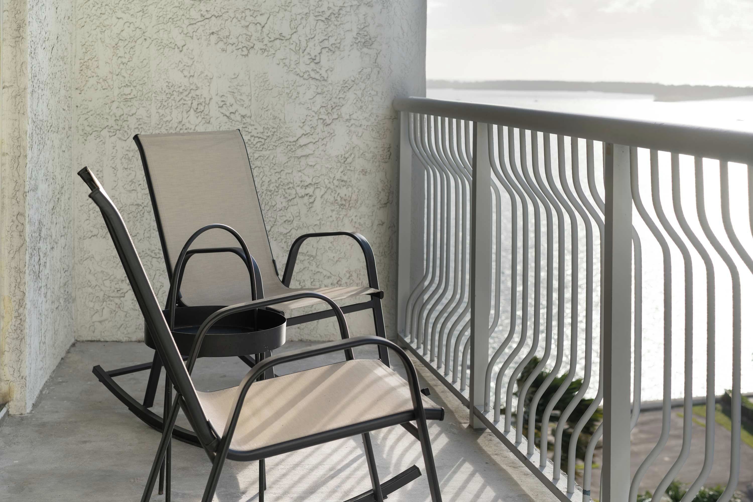 Un balcon avec deux chaises et une balustrade blanche.