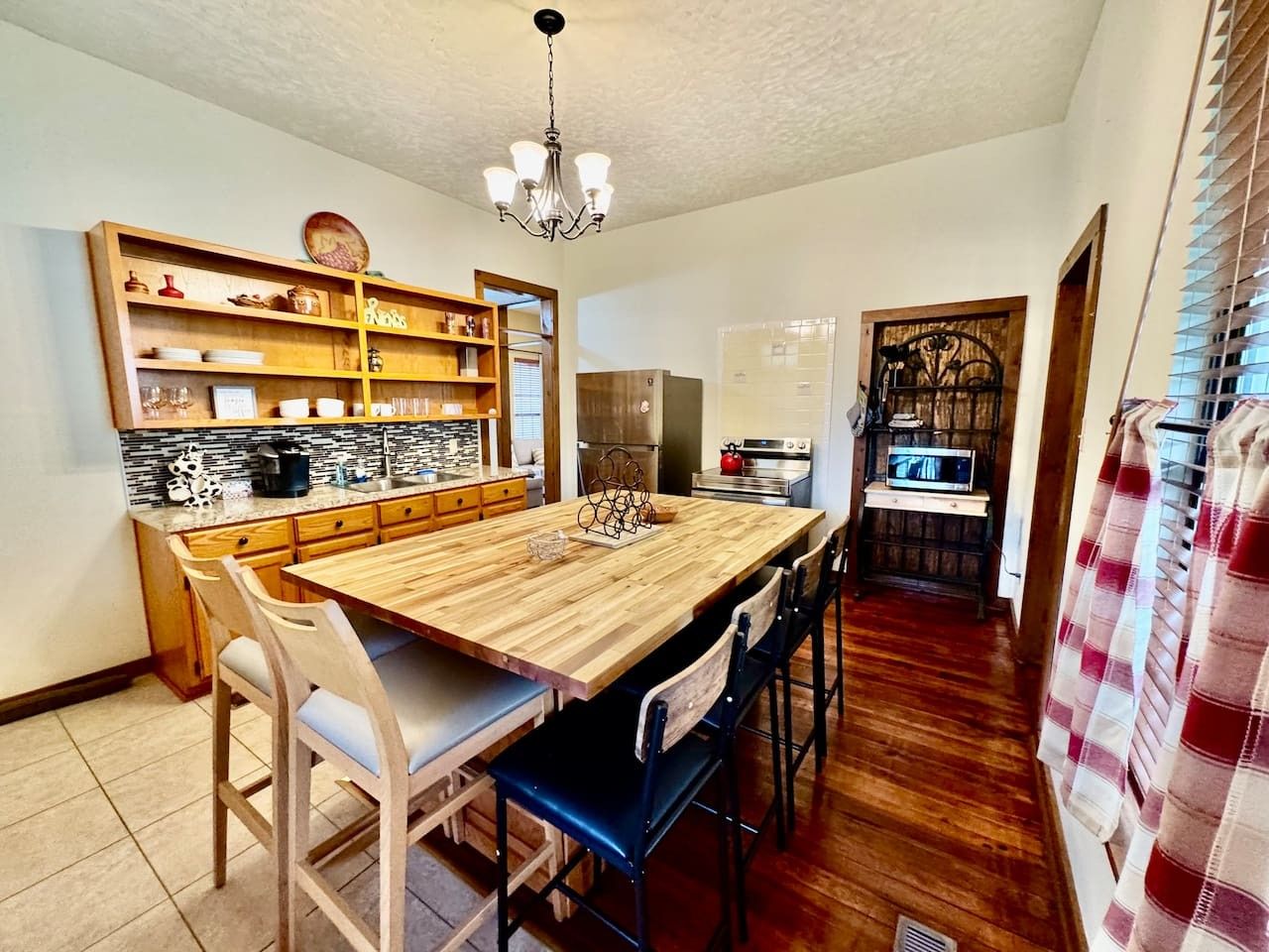 A kitchen with a wooden table, chairs, a chandelier, and a built-in shelf with various items.