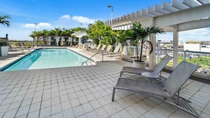 Ein Poolbereich auf dem Dach mit Liegestühlen und einer Pergola.