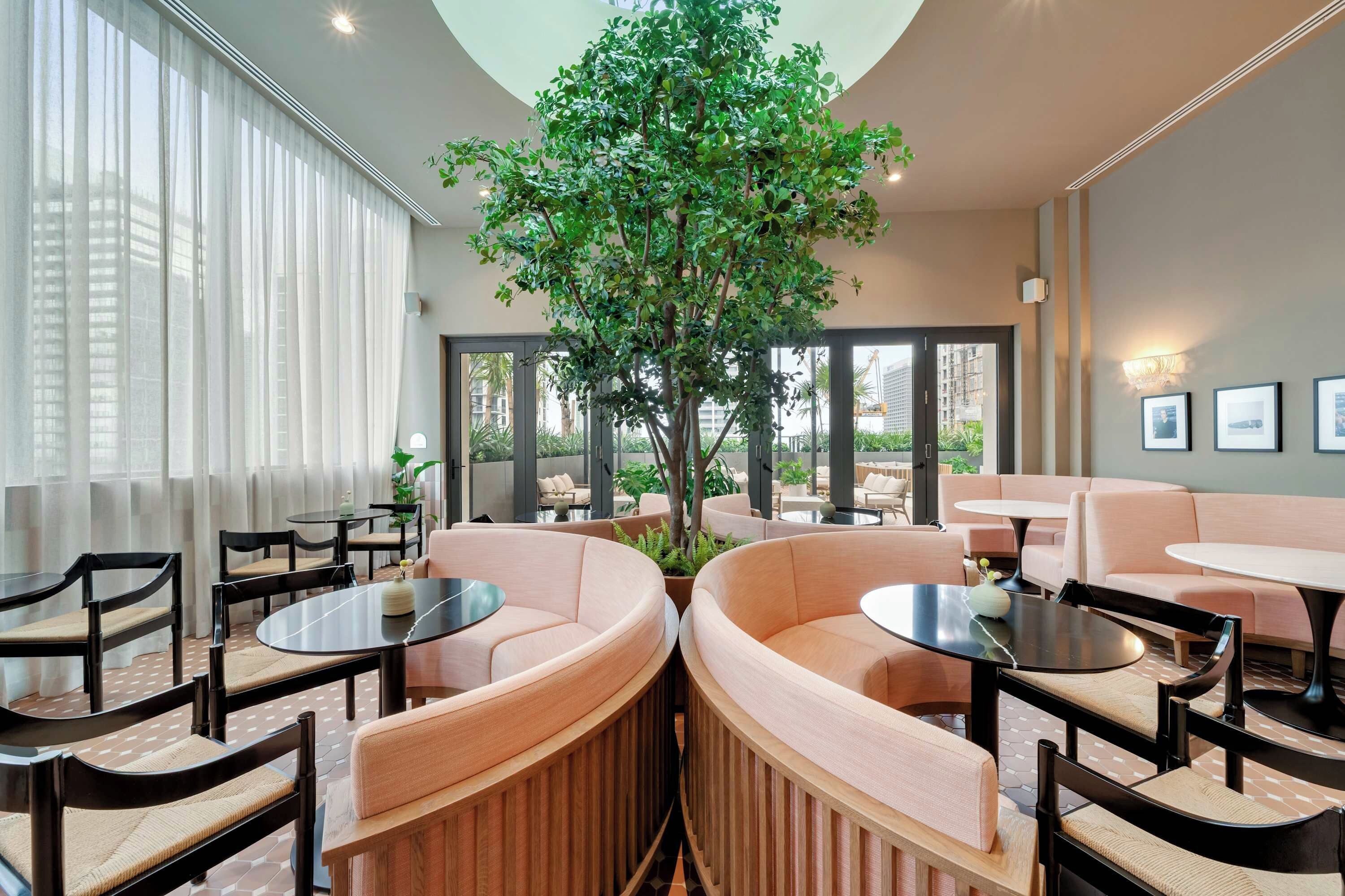 Un espace de détente moderne avec des sièges ronds, un arbre central et de grandes fenêtres.