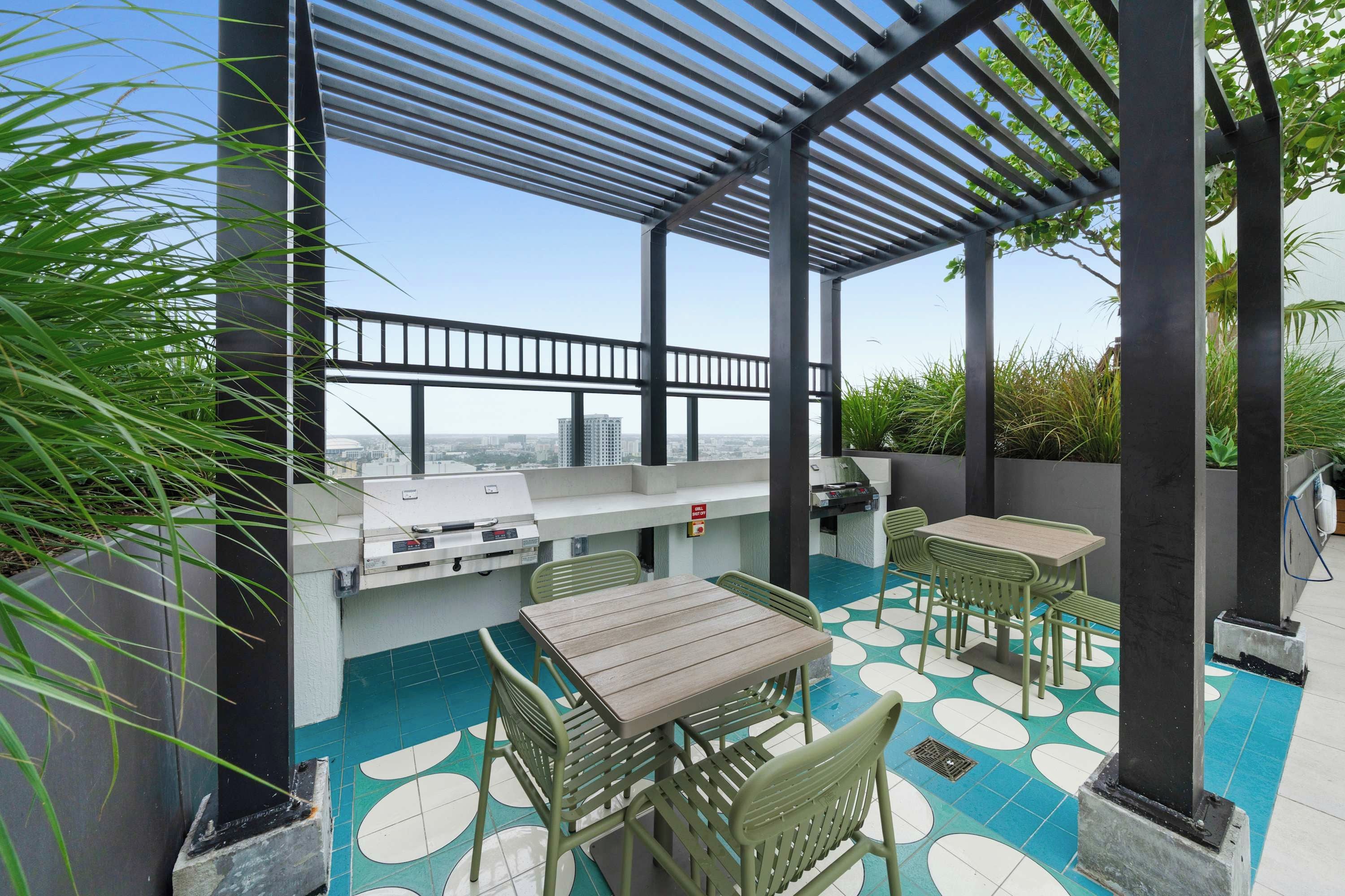 An outdoor patio with a grill, seating, and a view of the city.