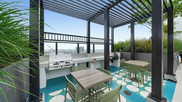 An outdoor patio with a grill, seating, and a view of the city.