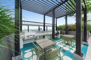 Eine Terrassengaststätte im Freien mit Grill, Sitzgelegenheiten und Blick auf die Stadt.