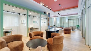 A modern office space with glass partitions, brown upholstered chairs, a central black table, and a red ceiling. - Sky Sanctuary With Rooftop Pool & Hot tub (Miami)