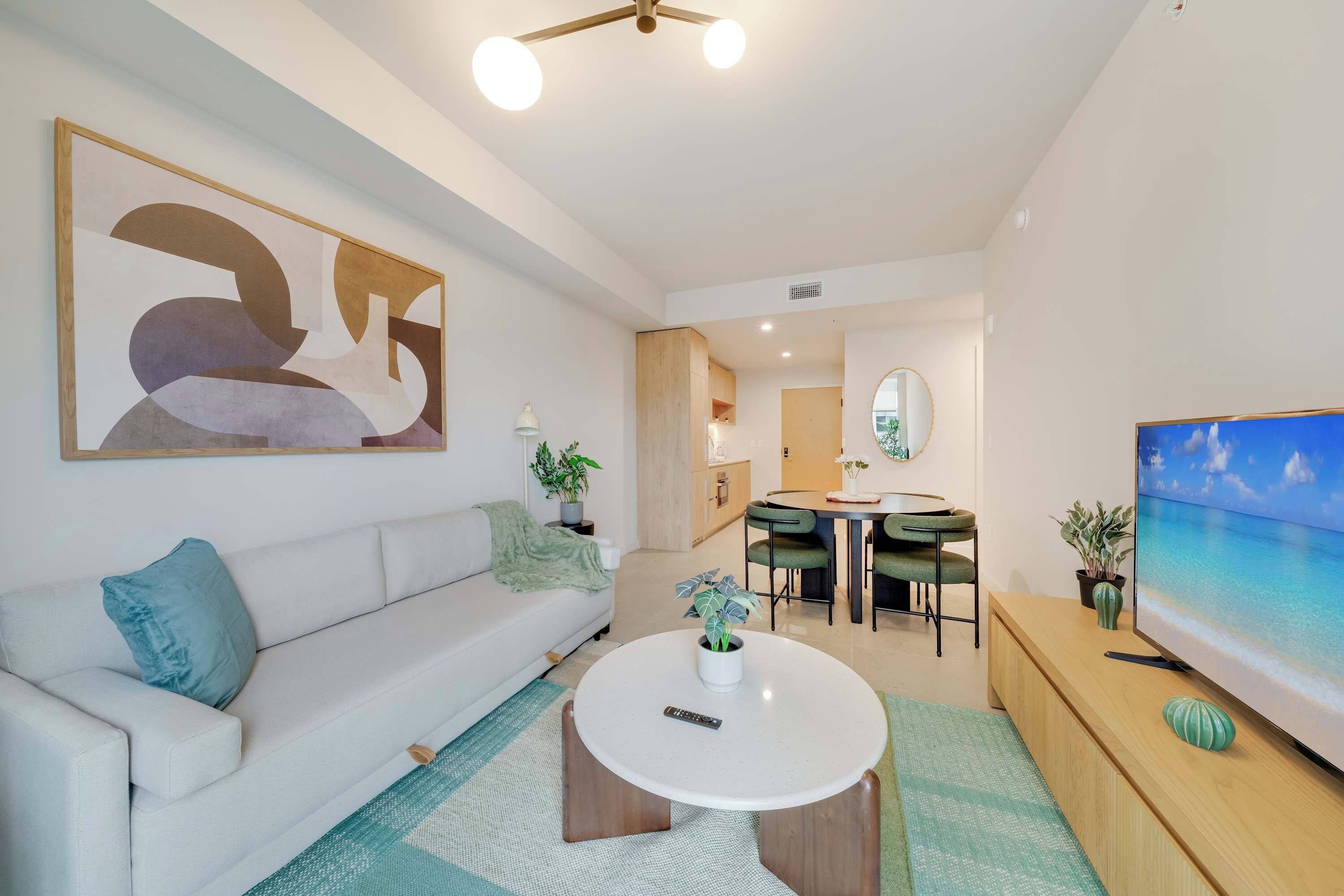 A modern living room with a white sofa, a round coffee table, and a TV on a wooden stand.